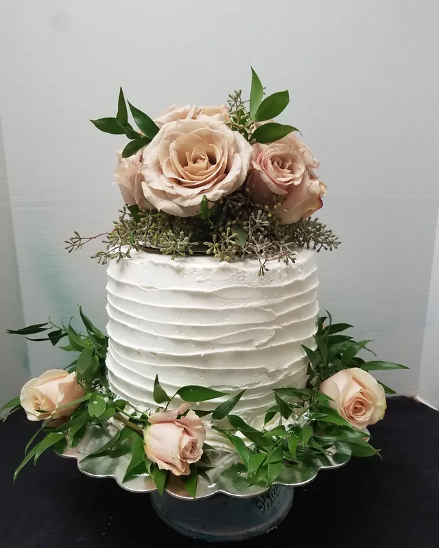 Rustic ruffled buttercream cake with blush roses and greenery