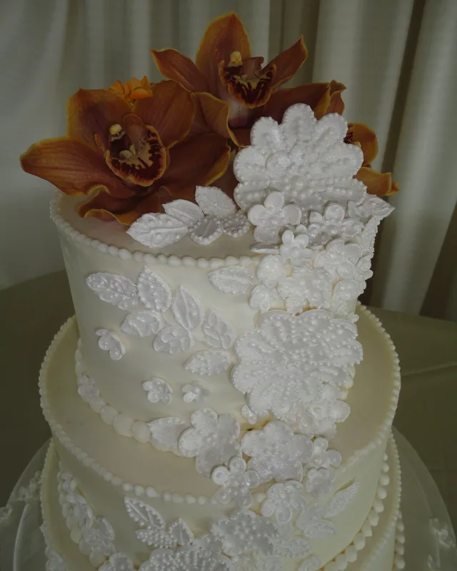 White cake with sugar lace appliqué and an orchid topper