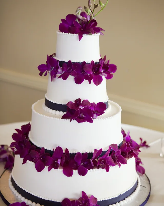 Tiered white cake banded with purple orchids