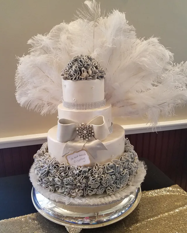 Cake topped with white ostrich feathers and silver sugar rosettes
