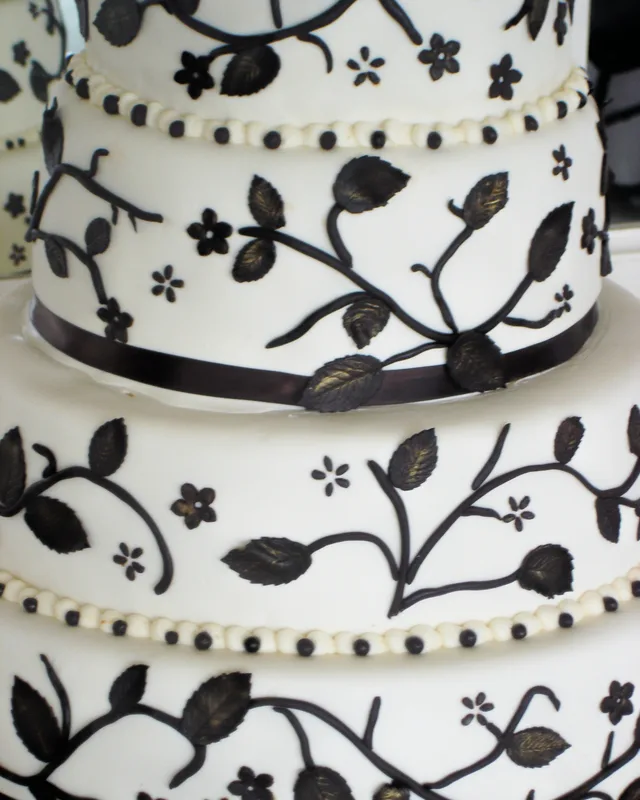 White cake with black piped vines and ribbon