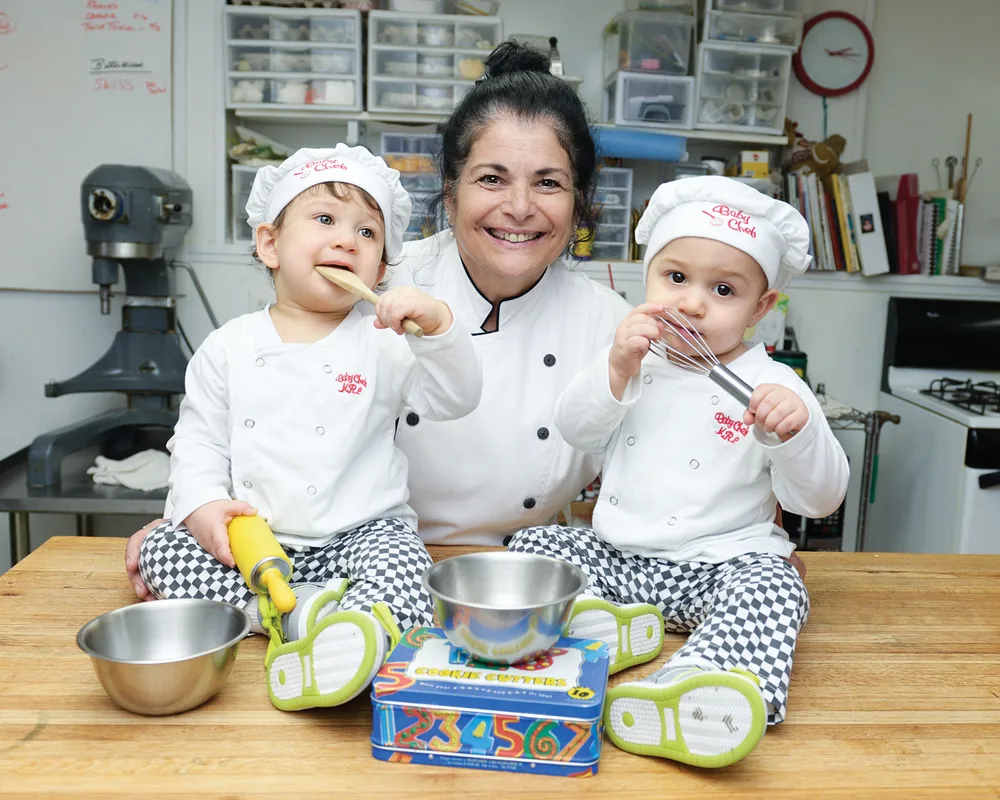 Chef Marlene Souza in her kitchen with two small children in chef hats